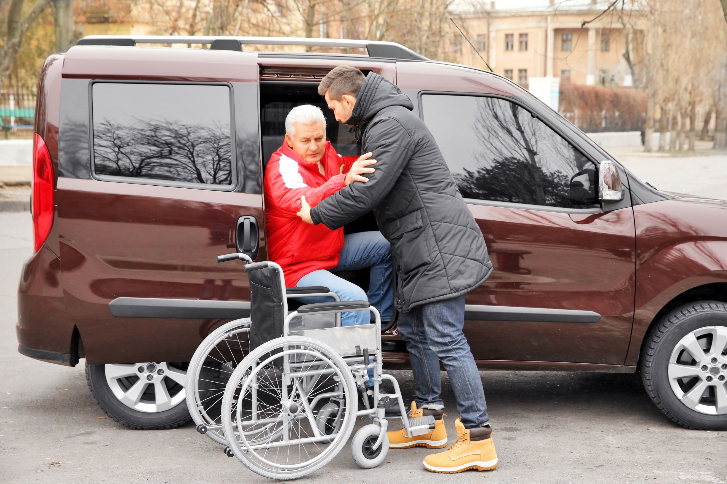 Taskm8 mate helping a man into a wheelchair from a car